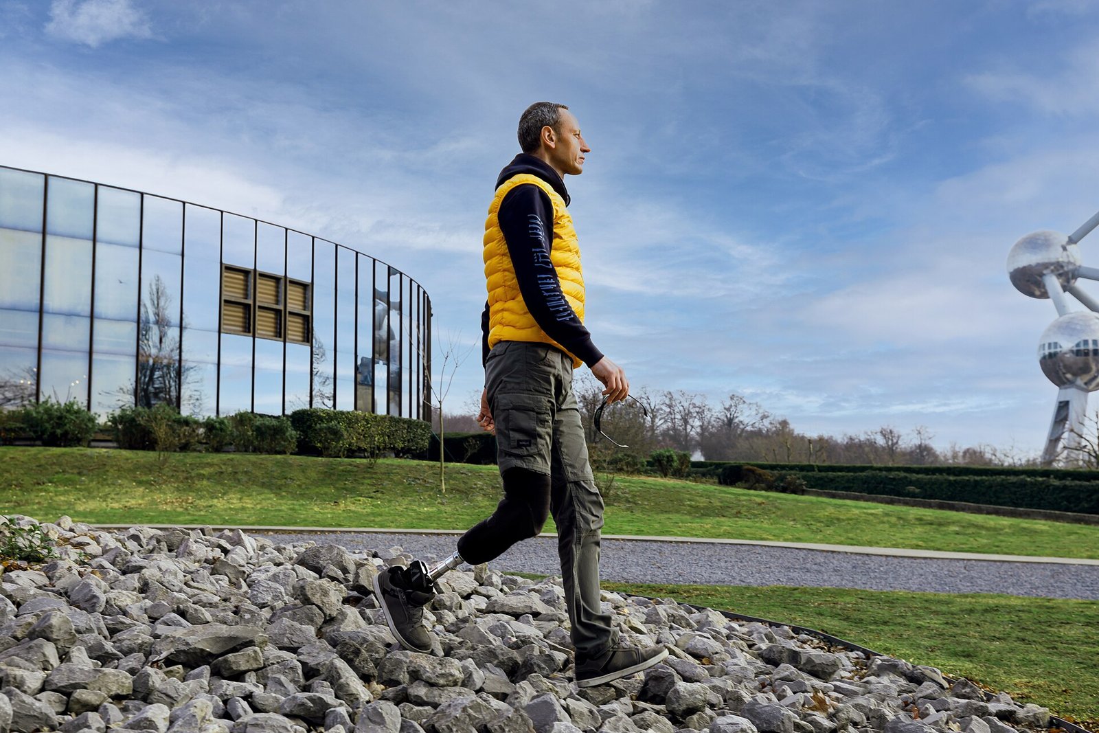 A man with a below-the-knee prosthesis walks across a path of stones